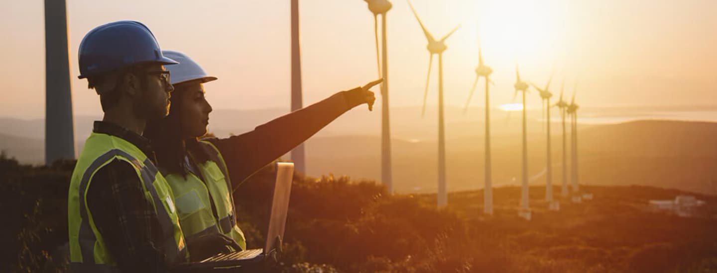 Two Engineers with security hermet in the field of wind turbines.